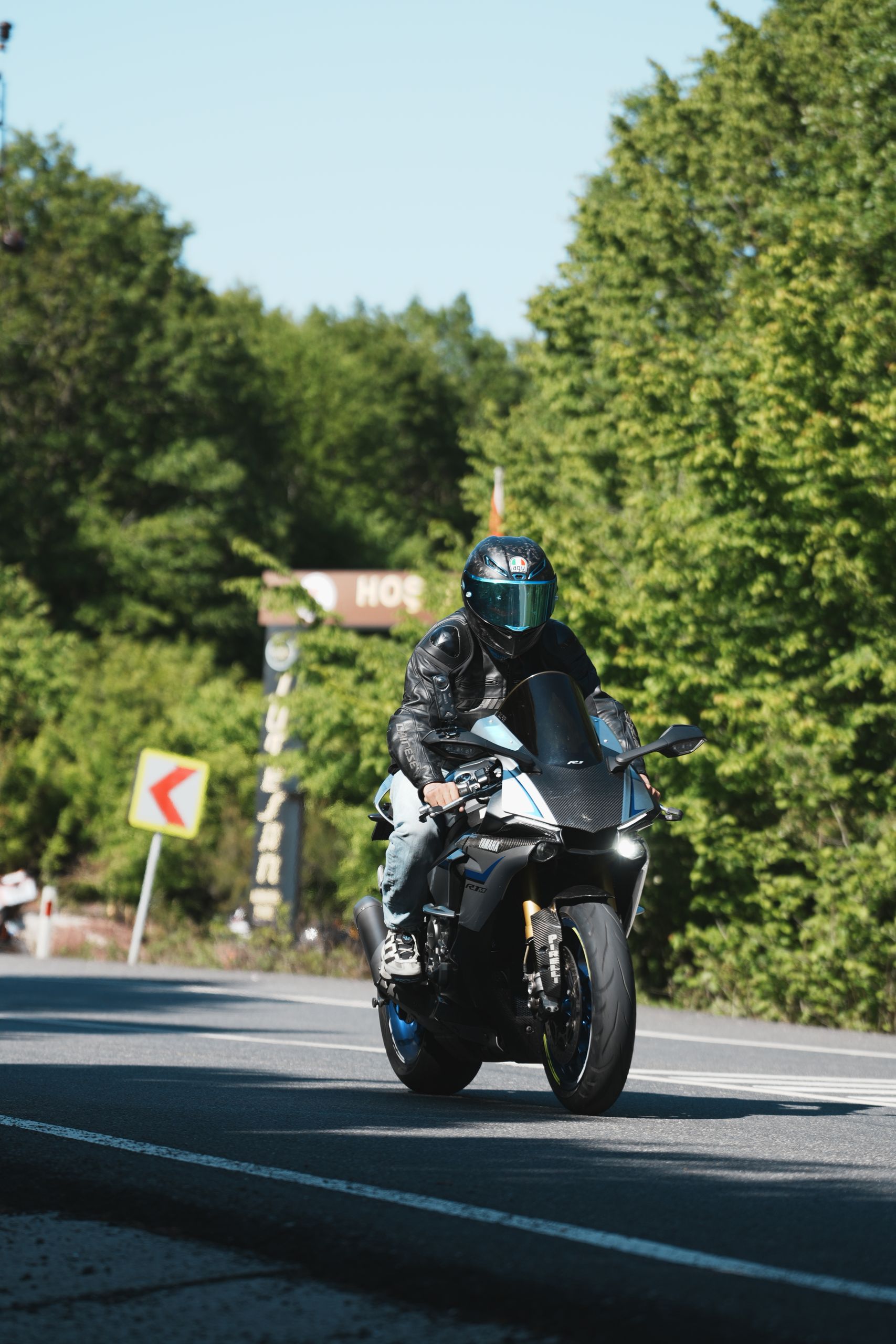A motorcyclist speeds on a scenic forest road during daylight.