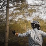 A motorcyclist wearing a helmet and gloves enjoys the tranquility of a forest environment.