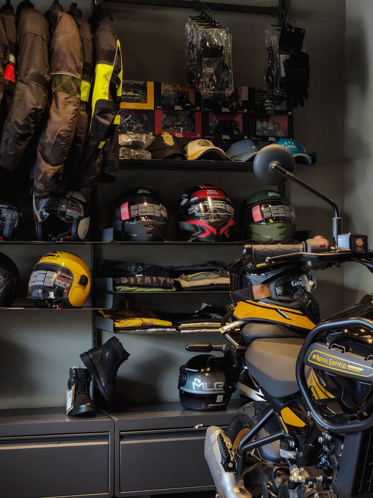Collection d'équipements moto : casques et accessoires en vrac — Asphalt RidersA collection of motorcycle gear including helmets and jackets in a showroom setting.