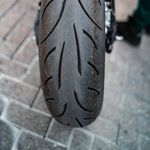 Detailed shot of a motorcycle tire on a city pavement, showcasing tread patterns and license plate.