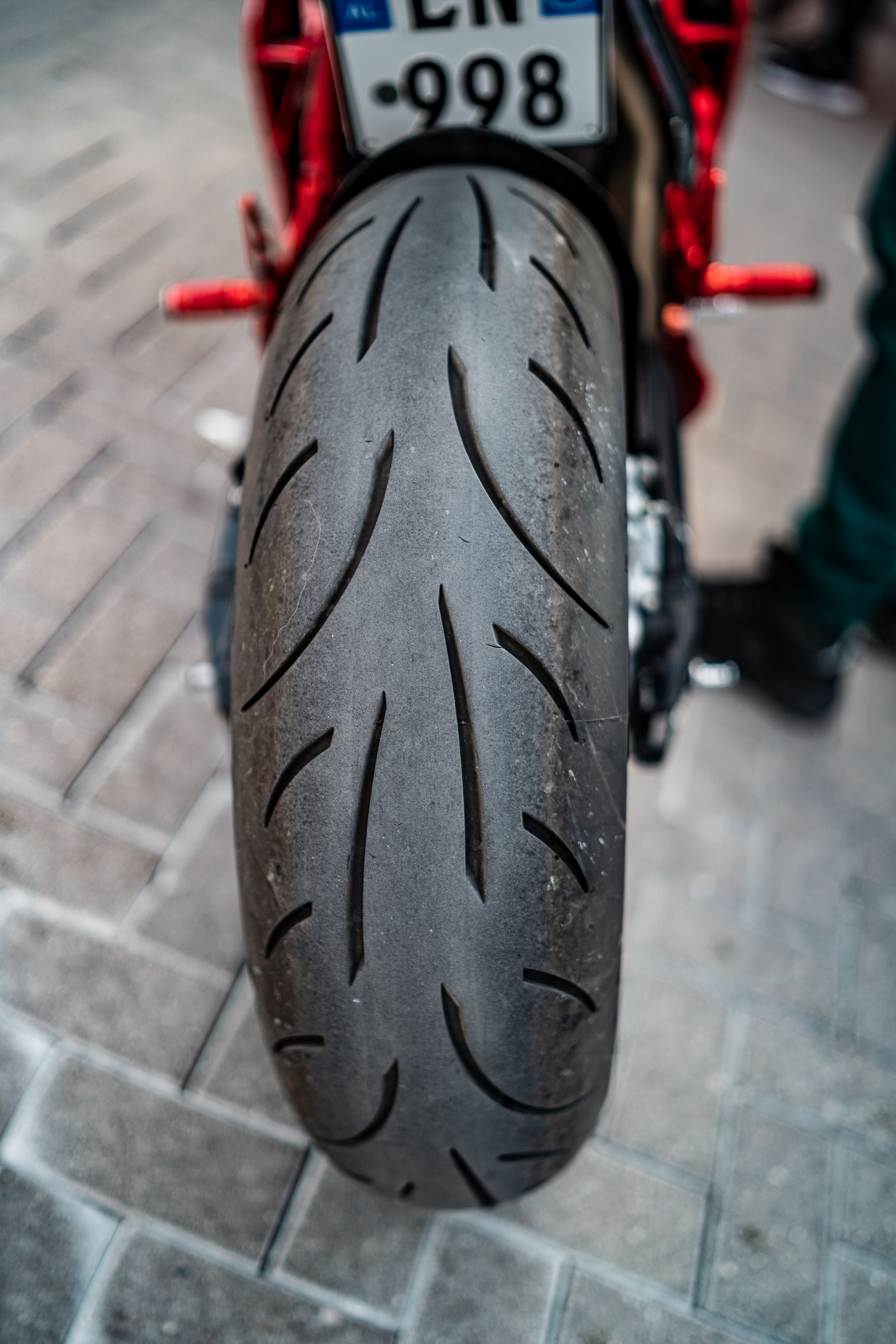 Detailed shot of a motorcycle tire on a city pavement, showcasing tread patterns and license plate.