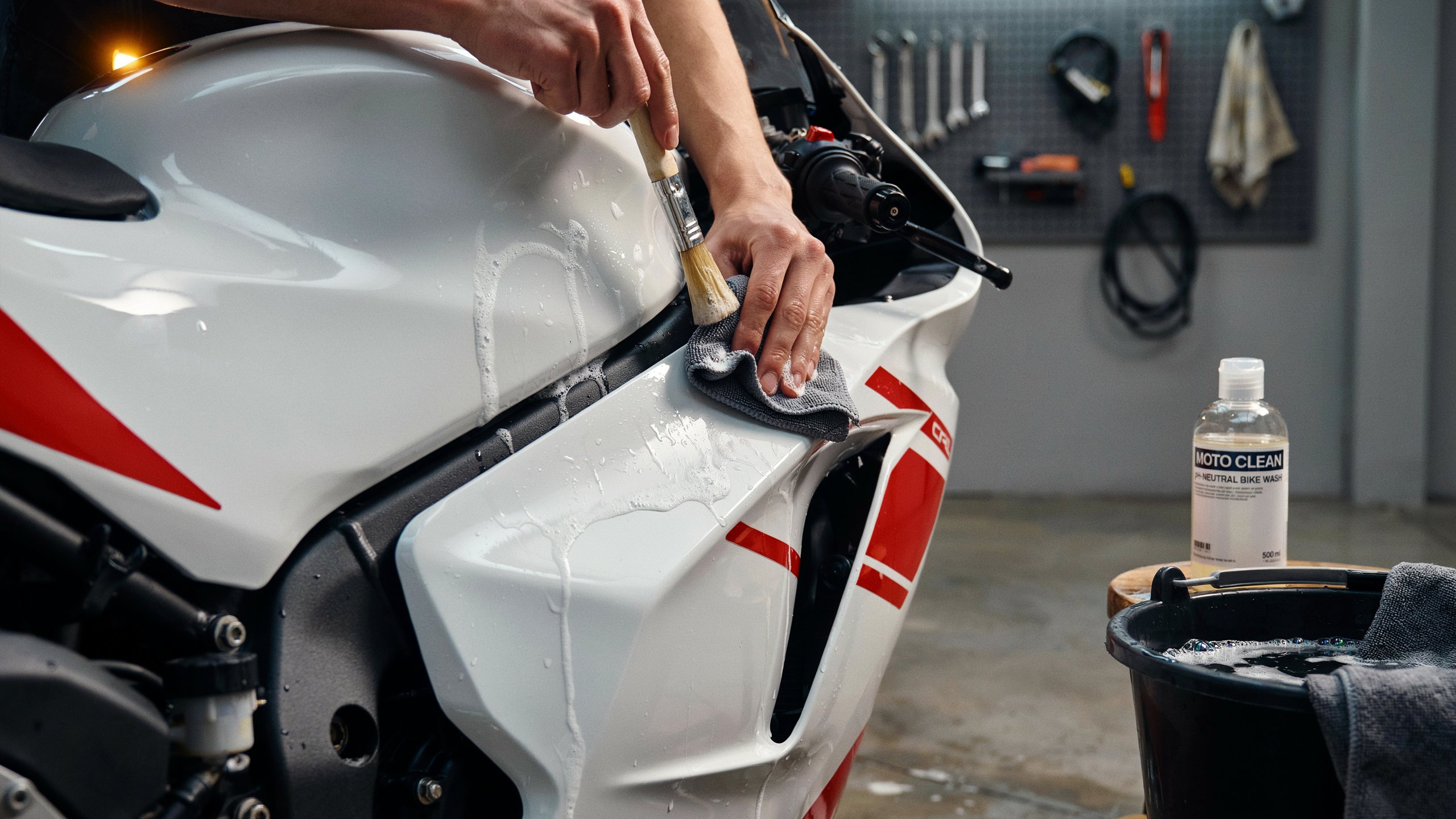 Comment nettoyer sa moto — brosse et microfibre sur carénage en garage