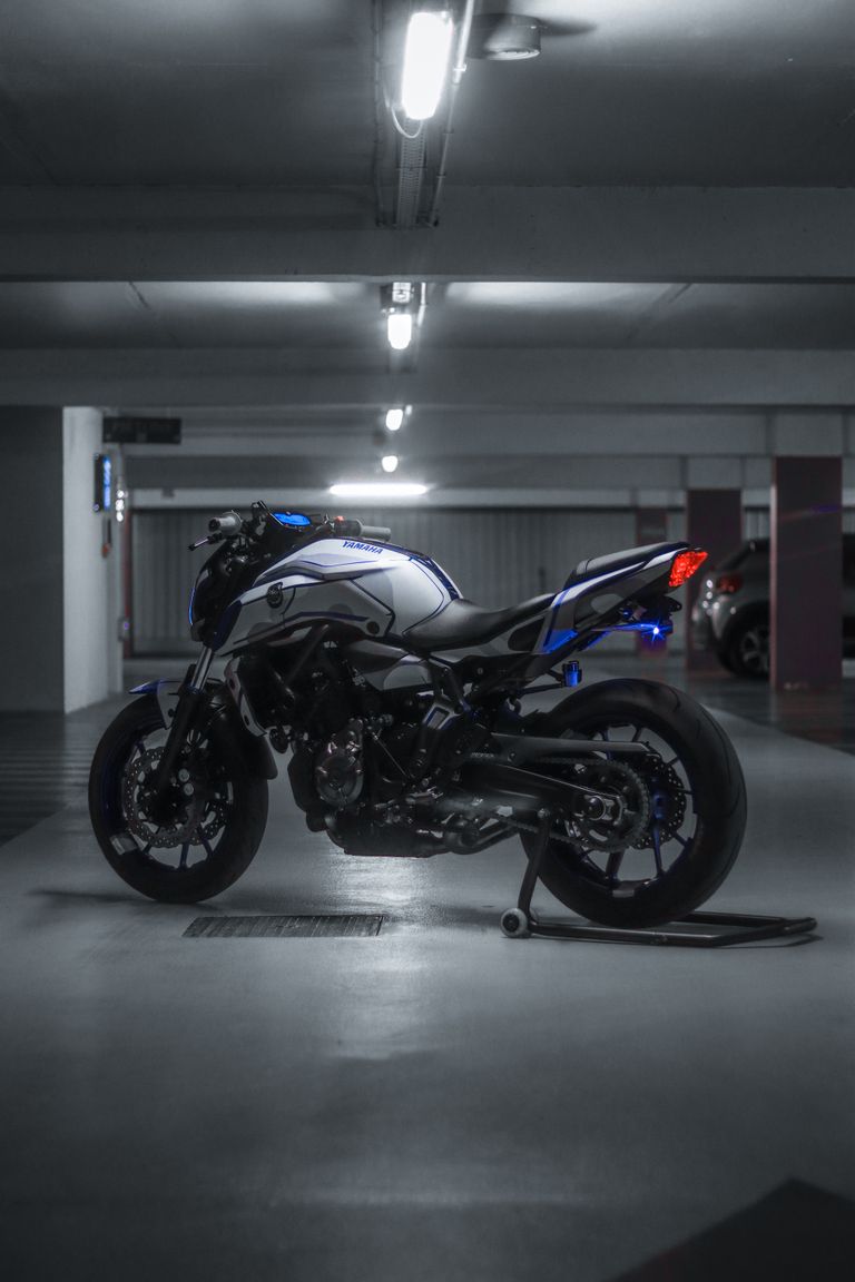 Moto naked bleue dans un parking urbain — Asphalt RidersHigh-performance sports motorcycle displayed in an urban underground garage, showcasing sleek design and power.