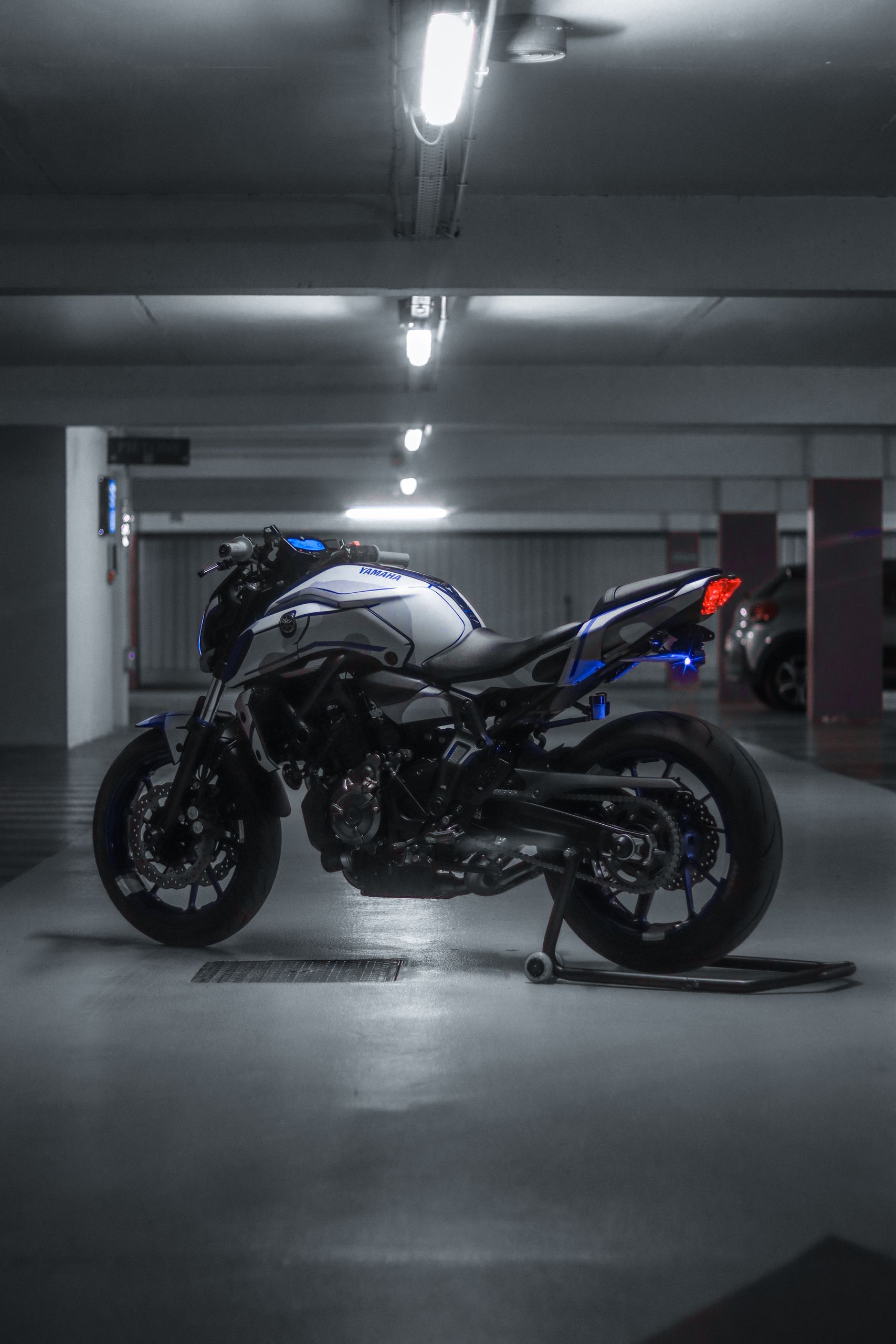 Moto naked bleue dans un parking urbain — Asphalt RidersHigh-performance sports motorcycle displayed in an urban underground garage, showcasing sleek design and power.